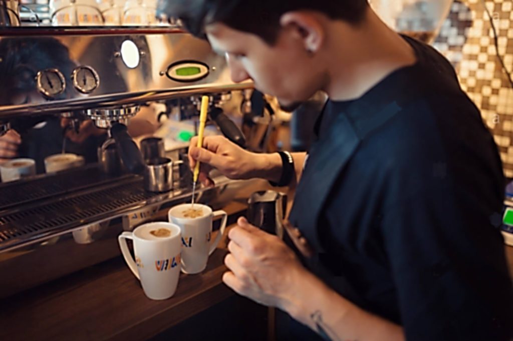 Barista working in coffee house making specialty coffee drinks